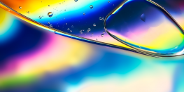 Macro shot of oil and water mixture with a vivid rainbow-colored backdrop.