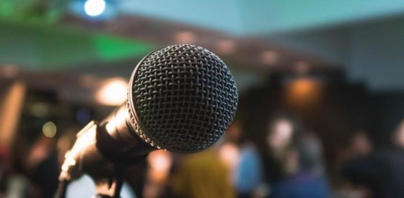 Close-up of a microphone with a blurred audience in the background.