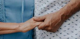 Close-up of a caregiver's hands gently holding a patient's arm, conveying support and care.
