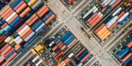 Aerial view of a shipping container yard with colorful containers arranged in rows.